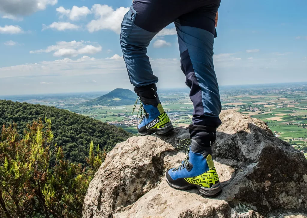 Escursioni in montagna con scarponi Gronell sulla cima di una montagna con panorama sulla pianura sottostante